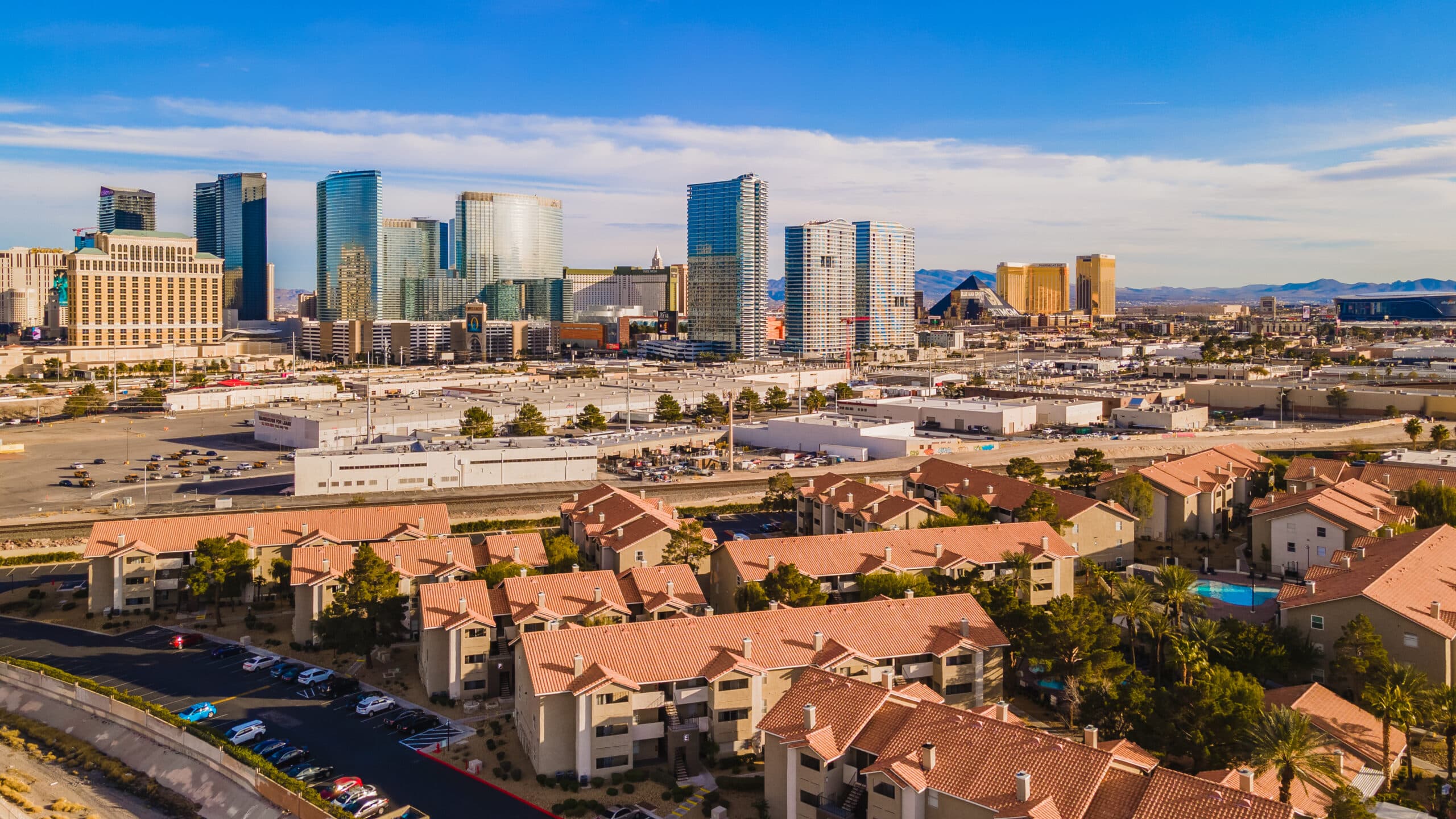 Aerial view of a city skyline with glass skyscrapers and a foreground of red-tiled houses