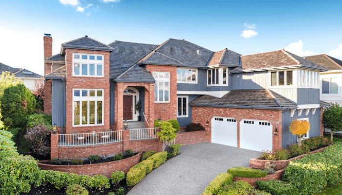 Two-story brick and blue siding house with a white double garage and landscaped front yard