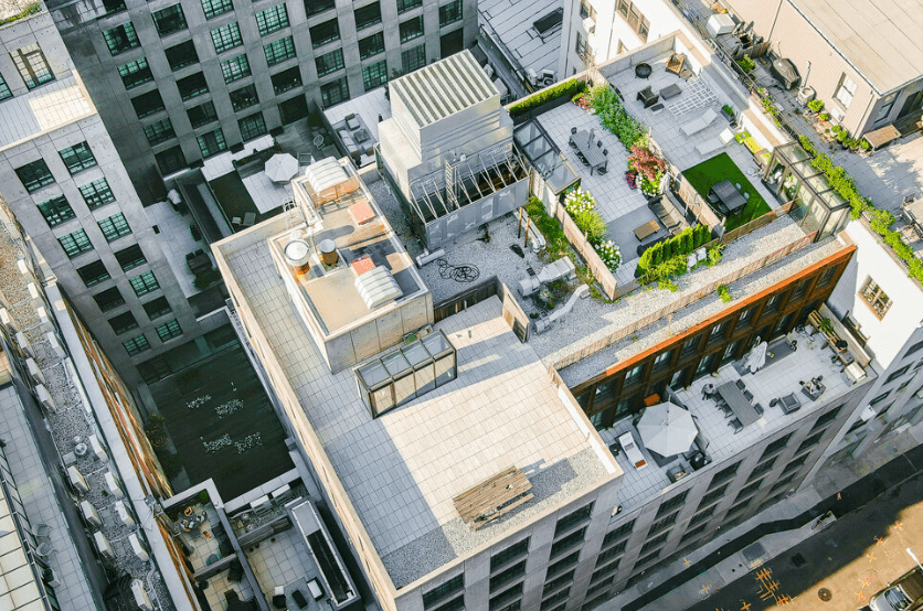 Aerial view of a rooftop terrace on a tall building with lounge seating and planters and greenery