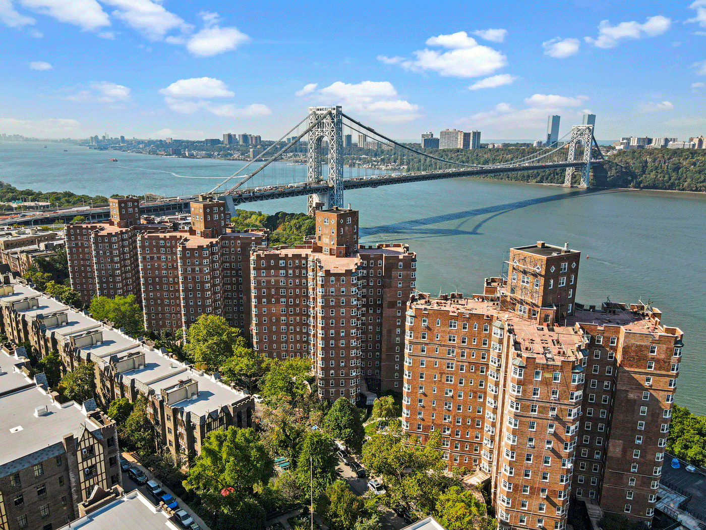 Suspension bridge over a wide river with brick apartment towers in the foreground