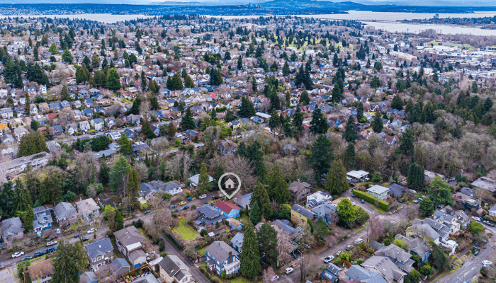 Aerial view of a suburban neighborhood with houses and trees, a location marker over a home