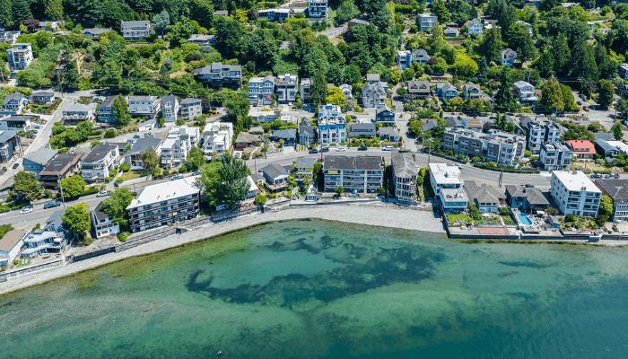 Aerial view of a coastal residential neighborhood with houses along a curved seawall and turquoise water