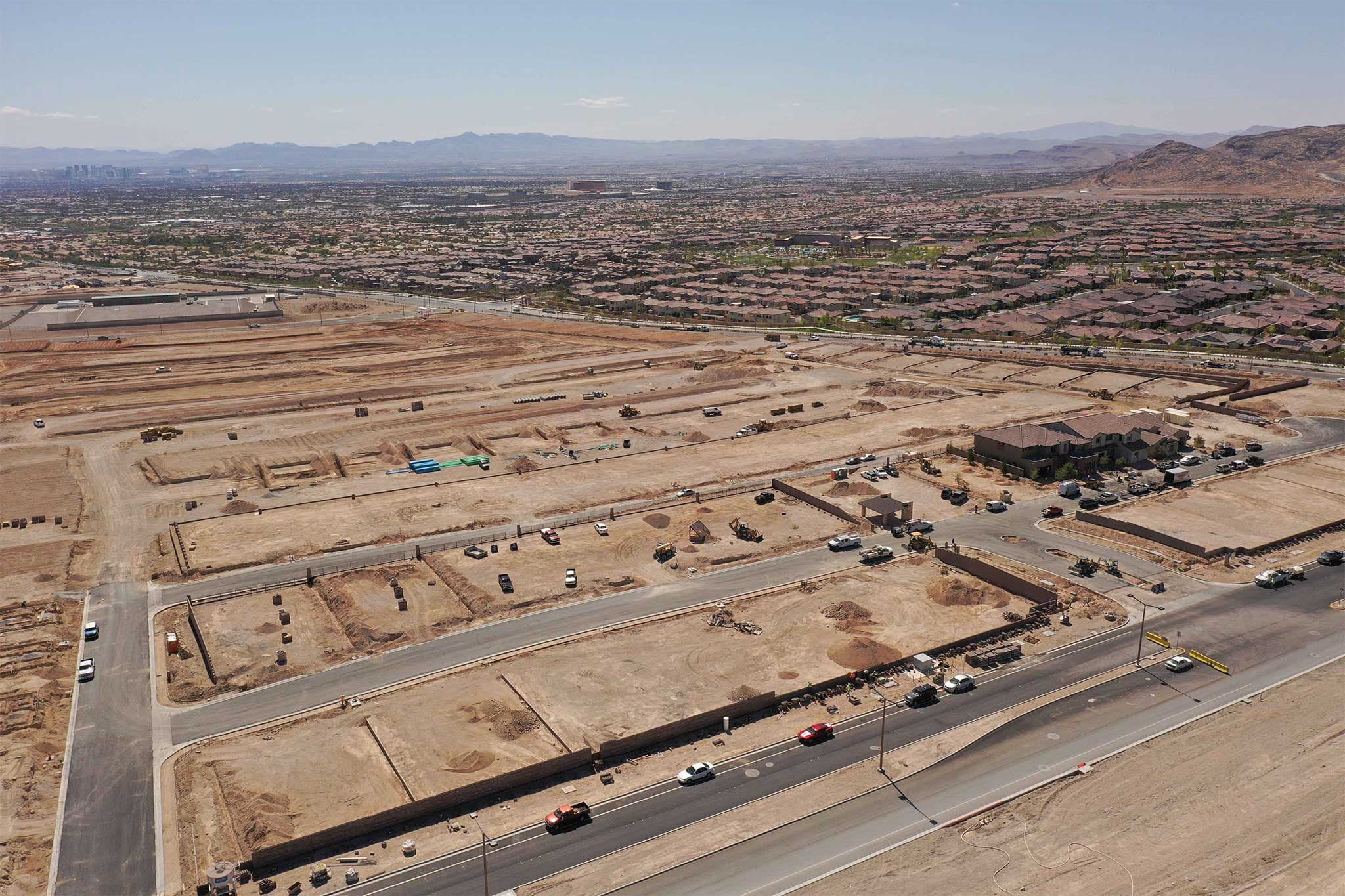 Aerial view of a suburban development with houses, roads, and cleared construction lots in a desert landscape