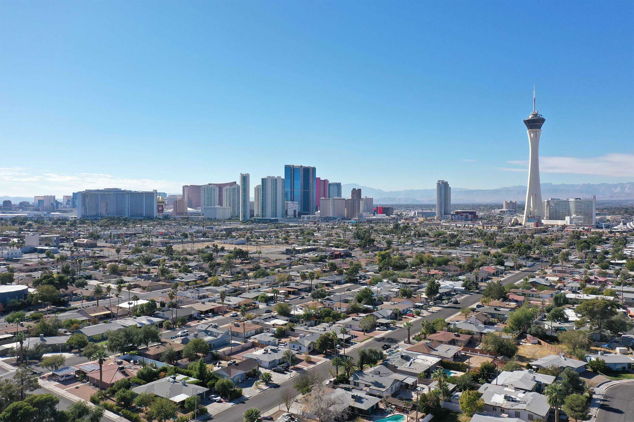 City skyline with high-rise buildings and a tall tower on the right, under a clear blue sky