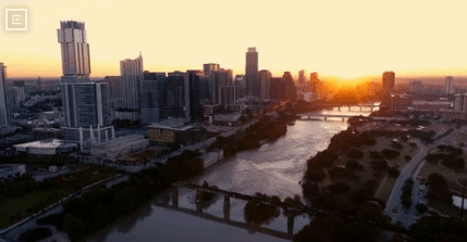Aerial view of a city skyline at sunset along a river with bridges and tall buildings