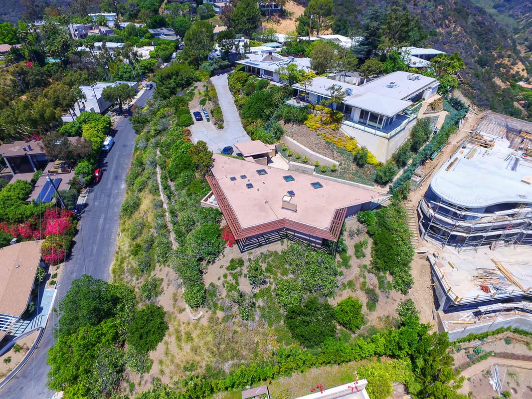 Aerial view of a neighborhood with a brown angular building at center and a construction site to the right