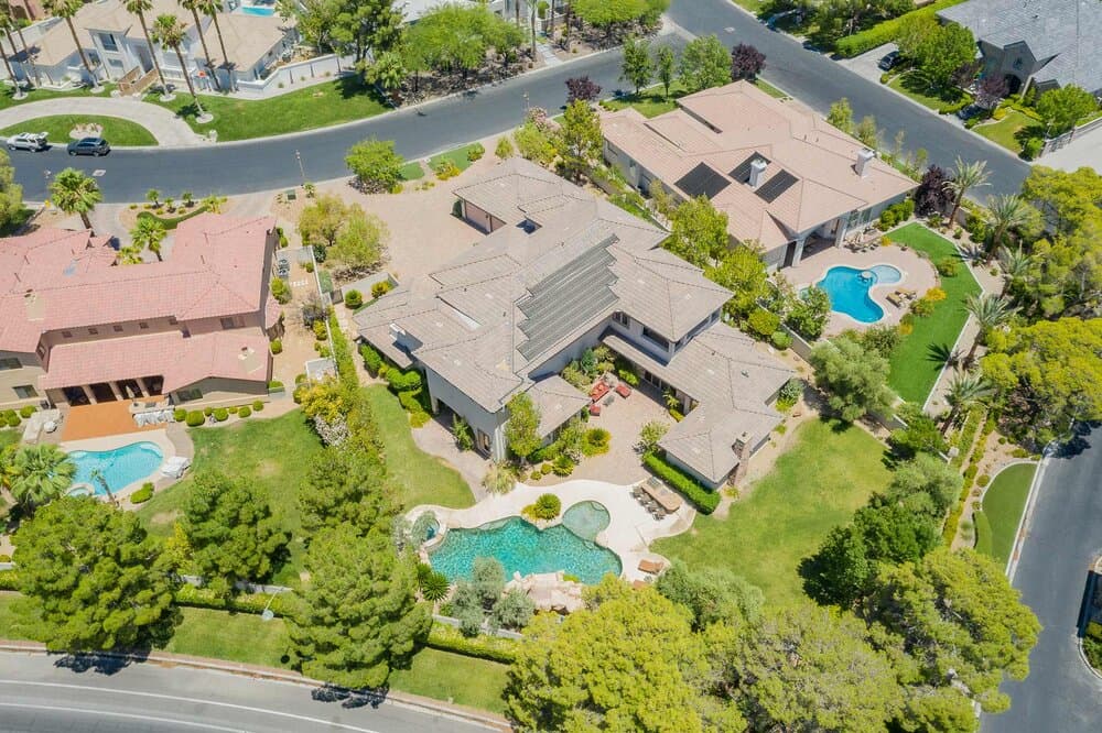 Aerial view of a suburban neighborhood with curved roads, large homes, and multiple backyard pools