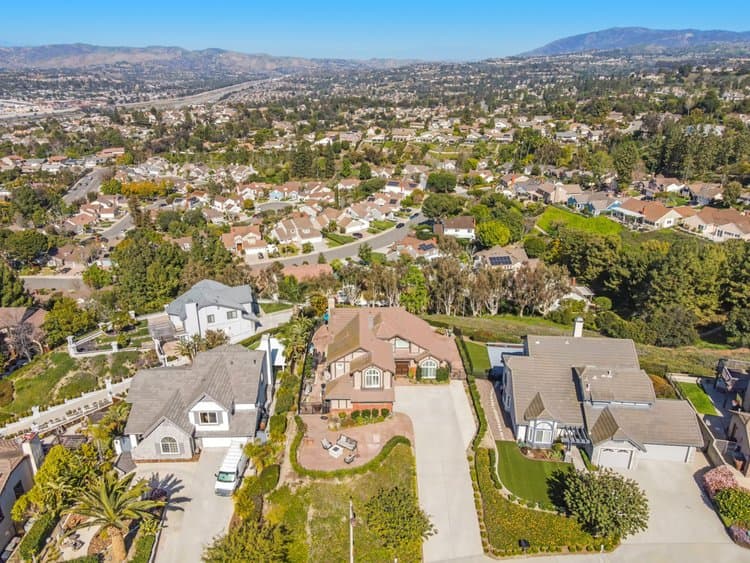 Aerial view of a suburban neighborhood with numerous houses, driveways, and green lawns