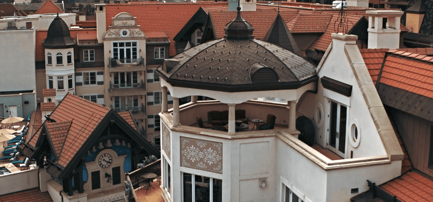 Rooftop terrace with a domed pavilion and outdoor seating, surrounded by red-tiled roofs
