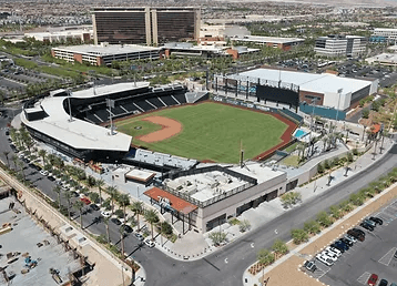 Aerial view of a baseball stadium with a green field, bleachers, and surrounding urban area