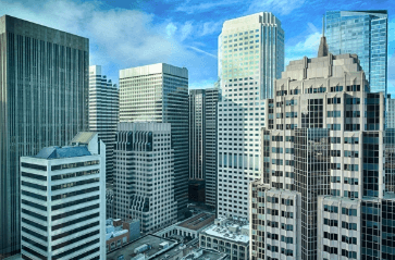 City skyline with tall glass skyscrapers under a blue sky, viewed from above